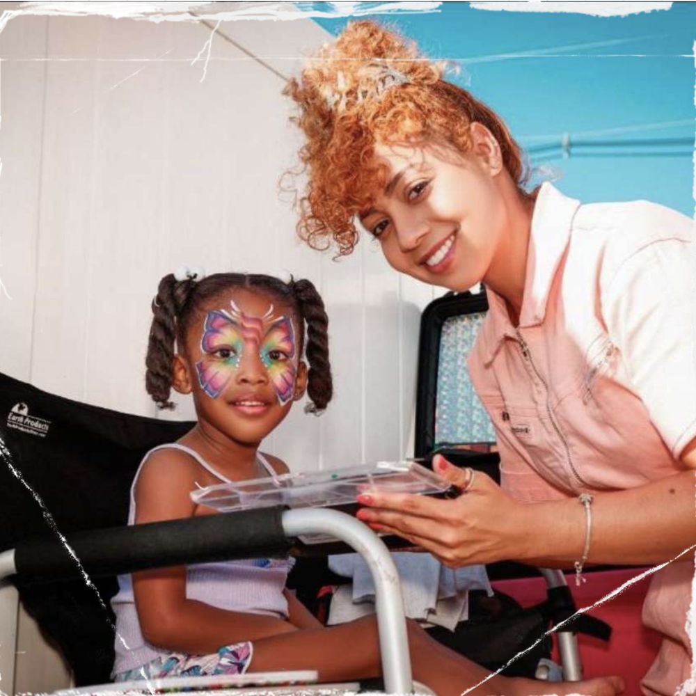 Face painter working on a child with colorful butterfly face paint